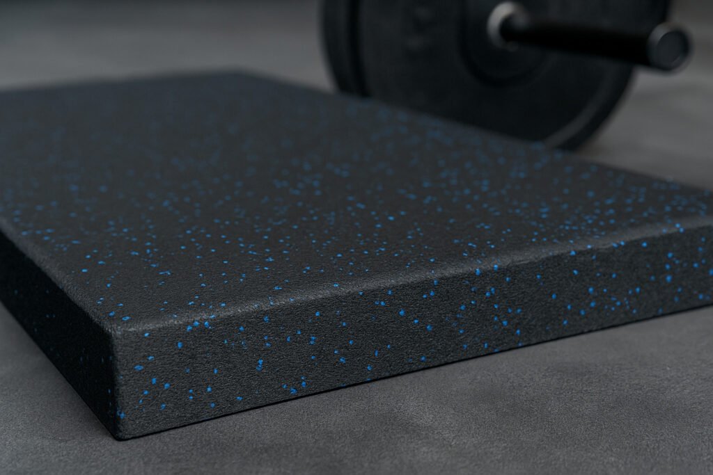 Close-up of durable black rubber gym tile with blue speckles, ideal for long-term use