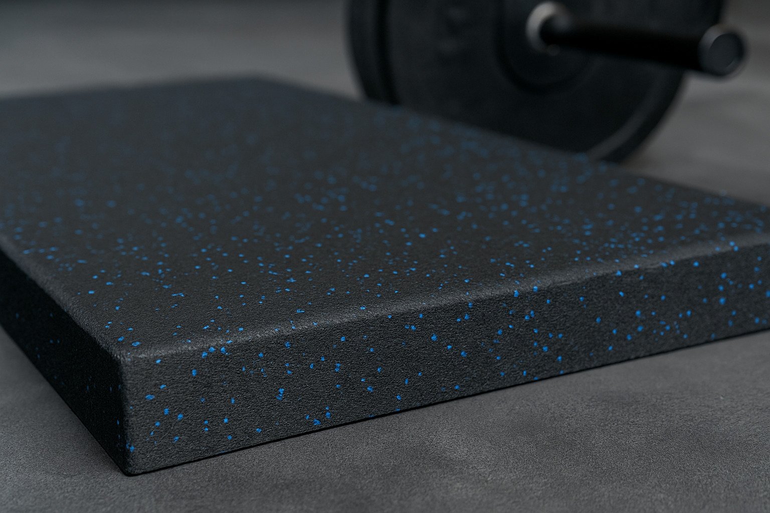 Close-up of durable black rubber gym tile with blue speckles, ideal for long-term use