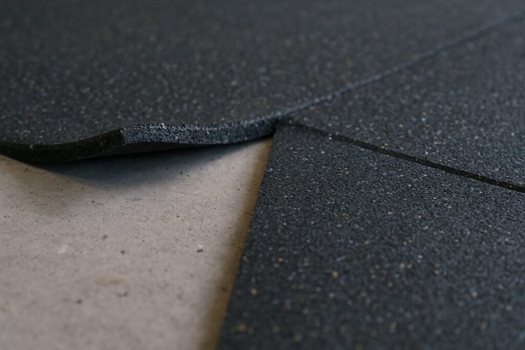 Close-up of rubber flooring roll lifting at seam during gym floor installation