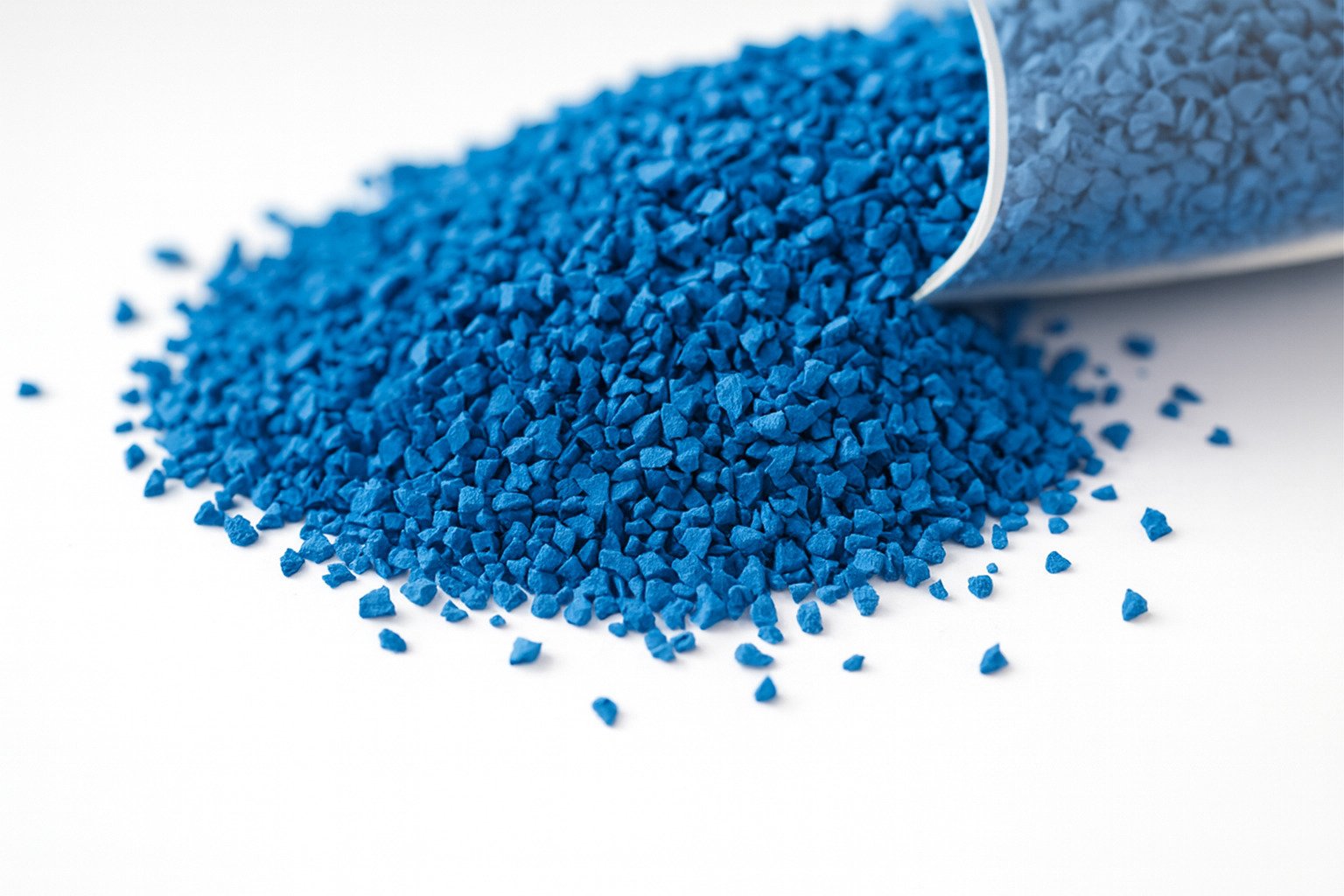 Close-up photo of bright blue EPDM rubber granules scattered on a clean white background, showing particle size and texture for wet pour playground flooring.